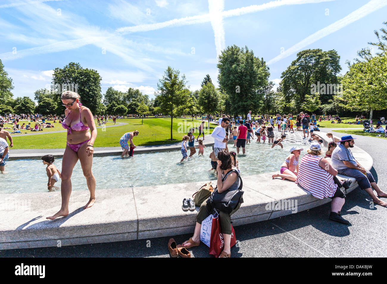 People enjoying summer at Princess Diana Memorial Fountain, Hyde Park, London, England, UK. Stock Photo