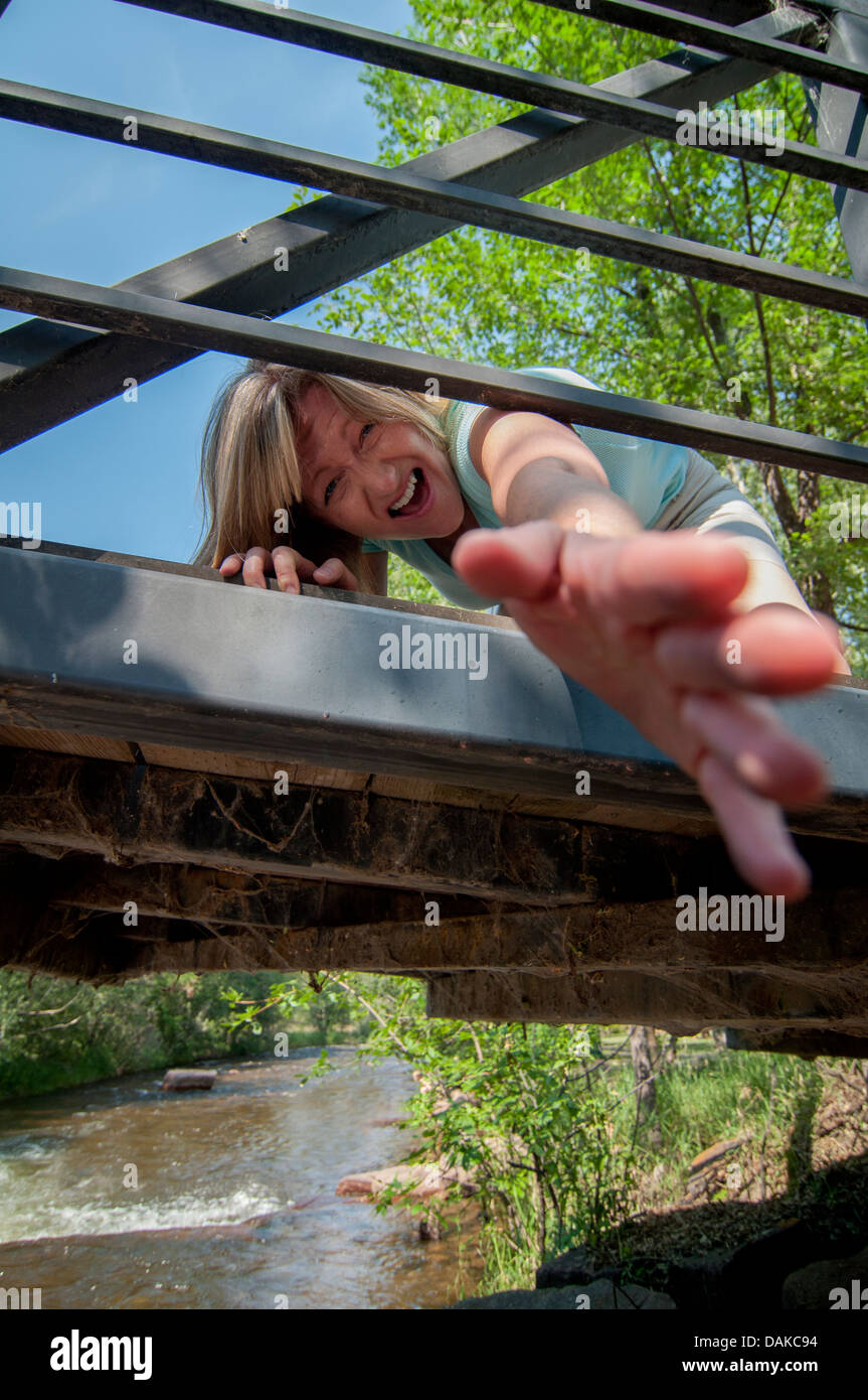 Woman reaching from bridge with hand outstretched. Stock Photo