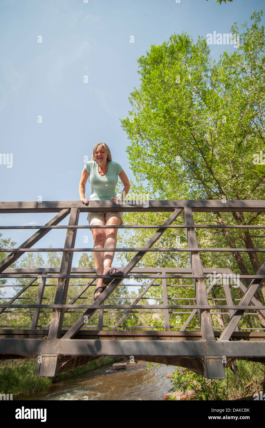 Woman on bridge railing looking over. Stock Photo
