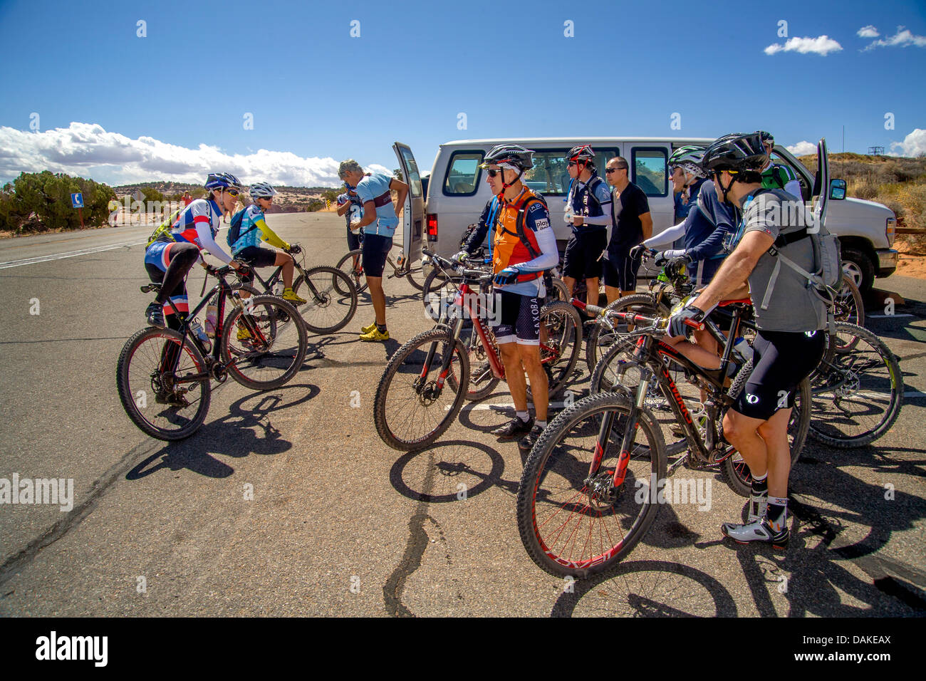 Wearing helmets and specialized clothing, an Italian mountain bicycle club greets two women members at Utah roadside. Stock Photo