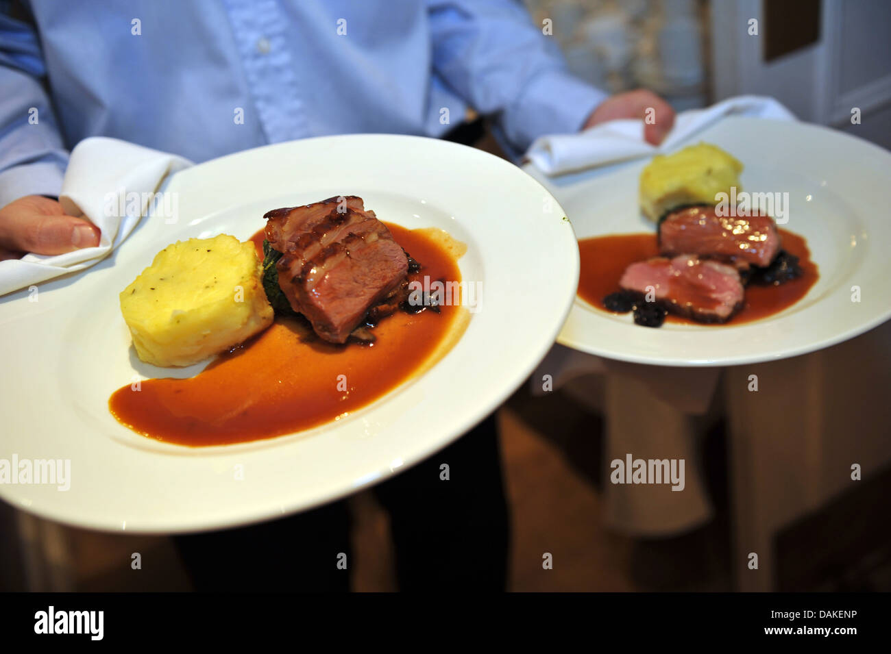 A waiter carries plates of food beef and mashed potato gravy. Stock Photo