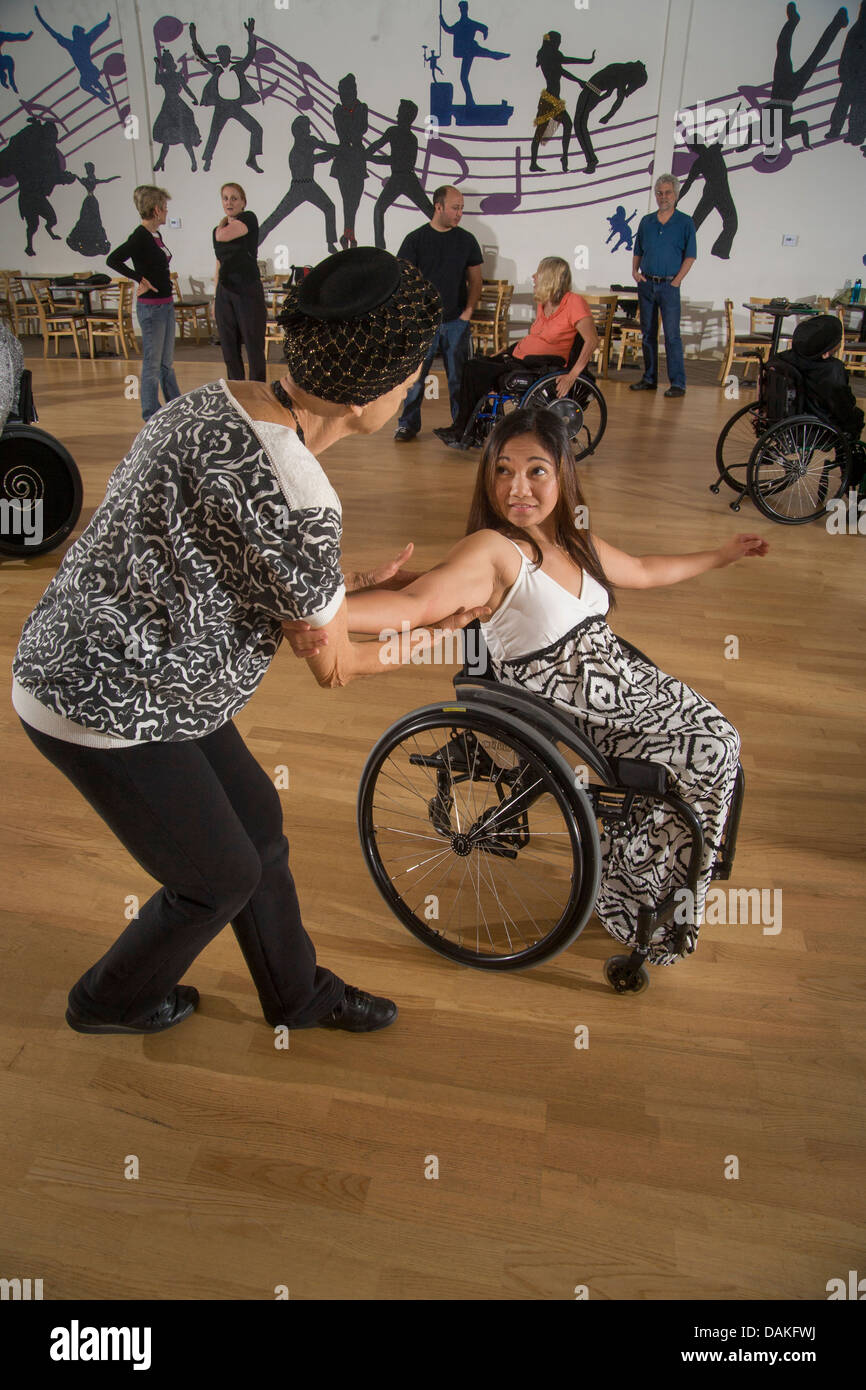 Physically able partner dances an Asian wheelchair dancing student in a