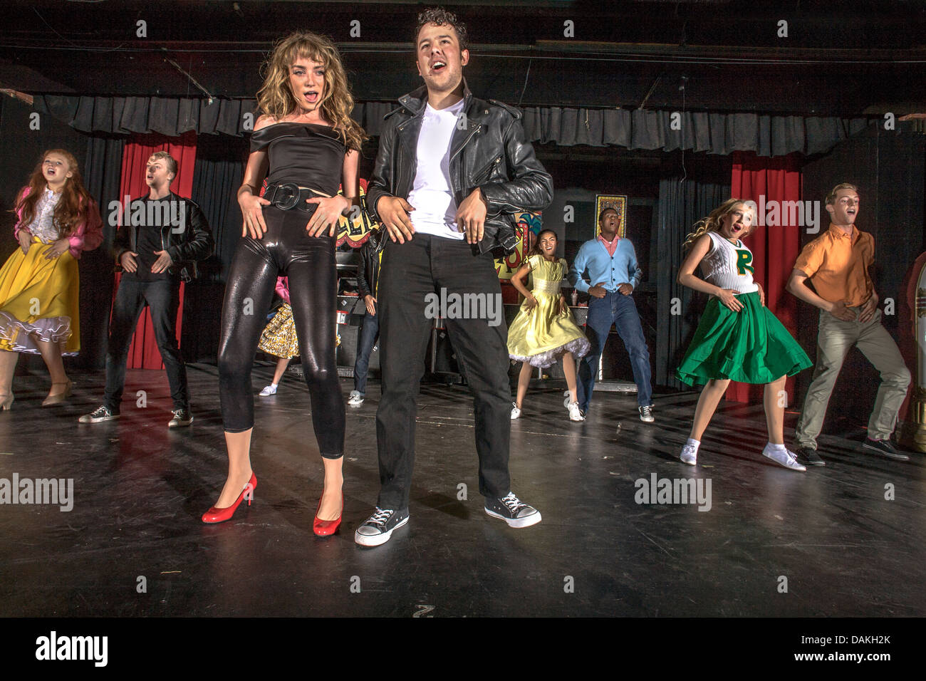 In 1950's clothing, Sandy Dumbrowski (left) and Danny Zuko lead the cast in ensemble number of a student production of 'Grease'. Stock Photo