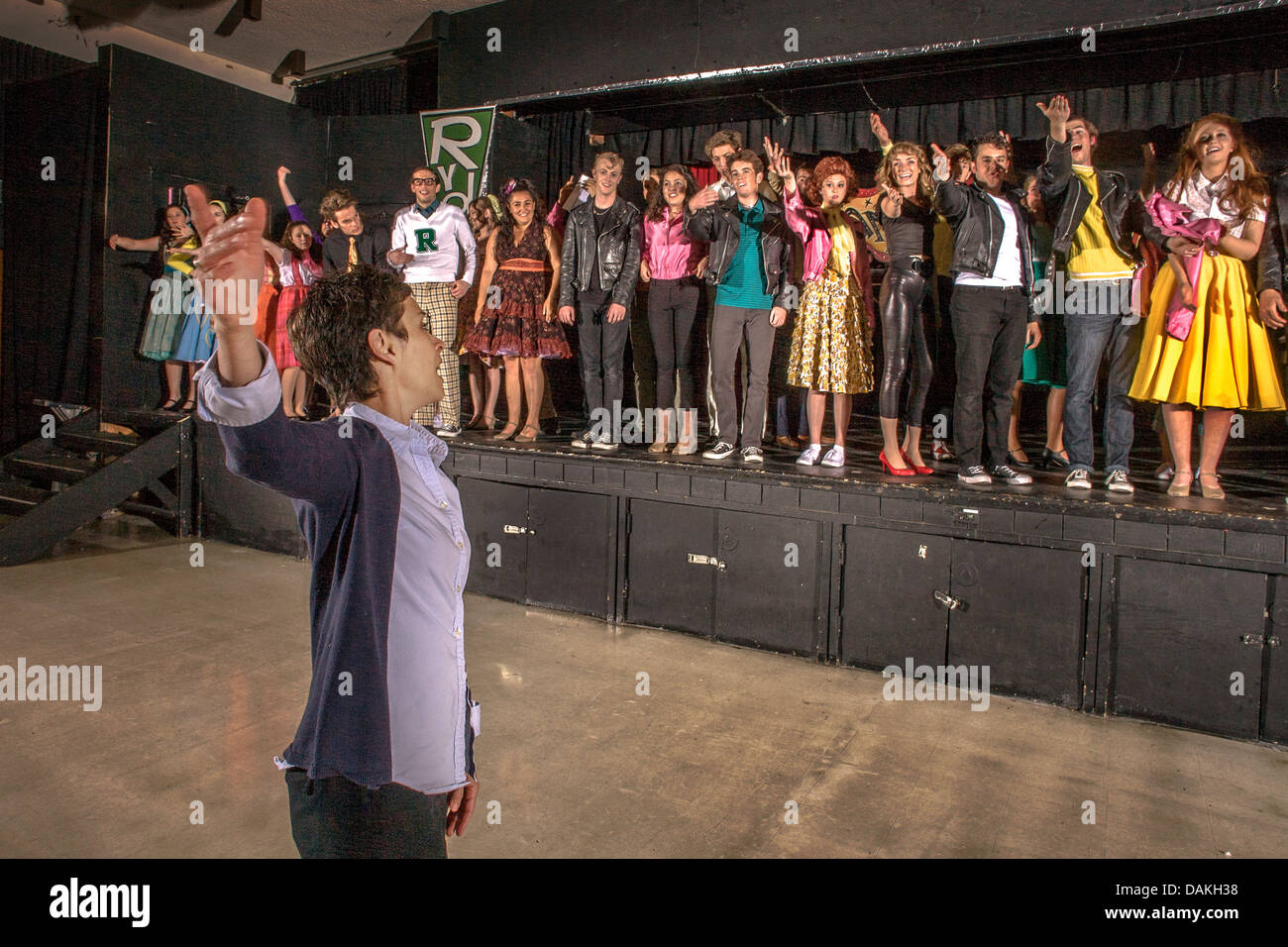 A drama teacher shows her students how to take a bow at the finale of a student production of the musical 'Grease' . Stock Photo