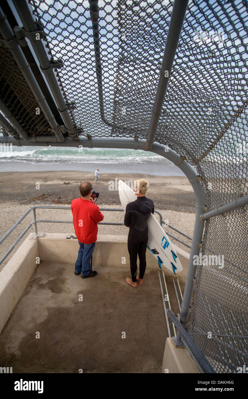 A teenage member of the San Clemente, CA, High School surfing team talks with the team coach after practice. Note camera. Stock Photo