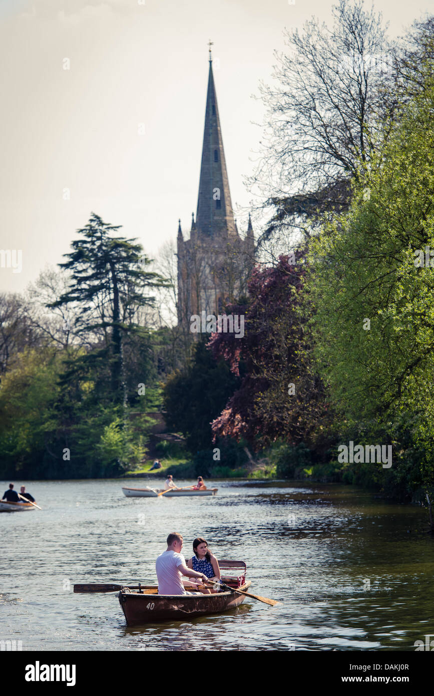 Couples boating on the banks of the river Avon in Stratford-Upon-Avon, United Kingdom with the Trinity church in the background Stock Photo