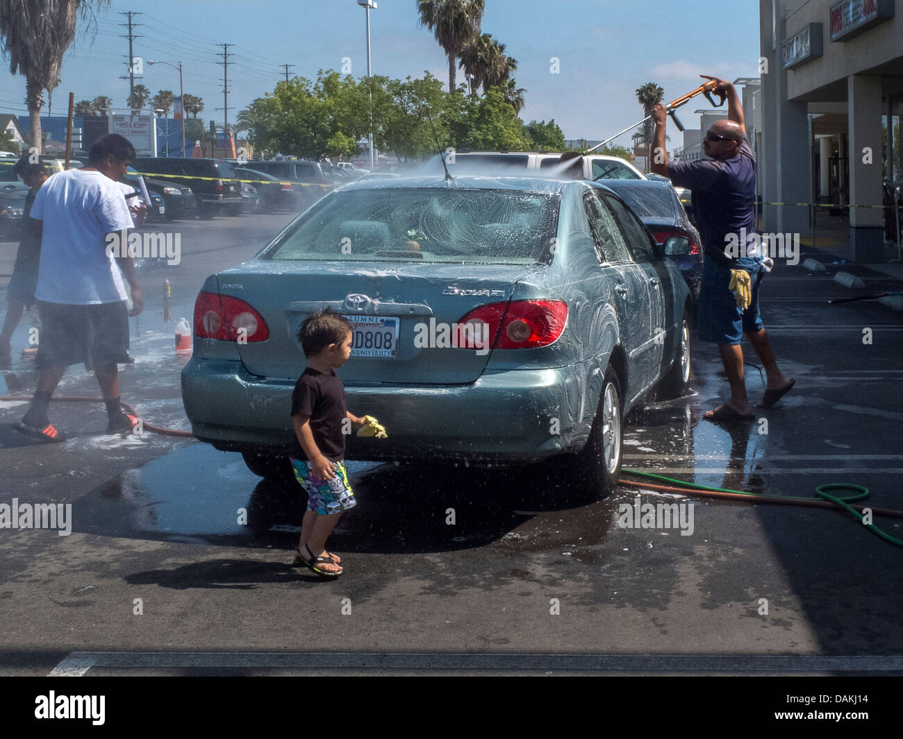 Multiethnic local children assist at a fund-raising charity car wash in a Southern California strip mall on a sunny afternoon Stock Photo