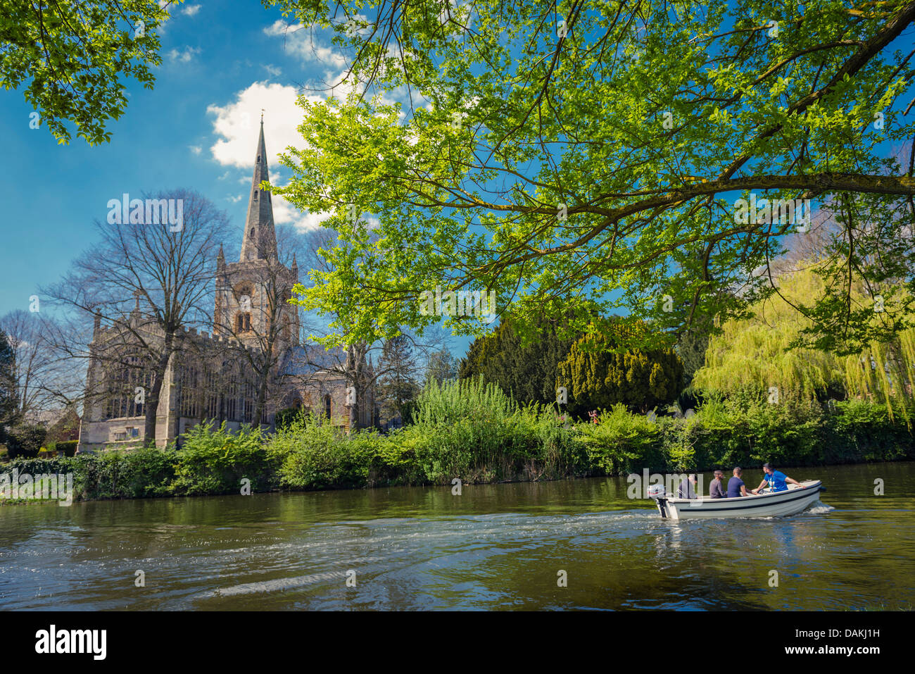 A motorboat on the river Avon in front of Trinity church on the banks of the river Avon in Stratford-Upon-Avon, United Kingdom Stock Photo