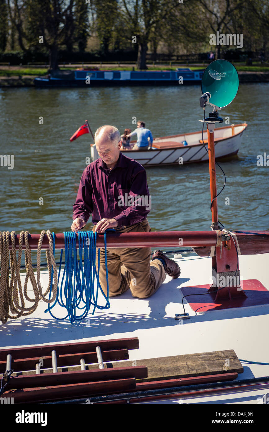 A man tying rope on a boat on the Thames, Richmond, London Stock Photo