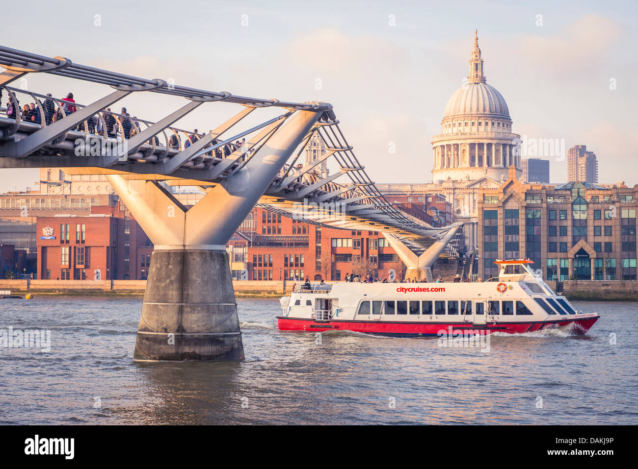 A tourist speed boat passes under the Millennium bridge, London with St. Paul's cathedral in the background Stock Photo