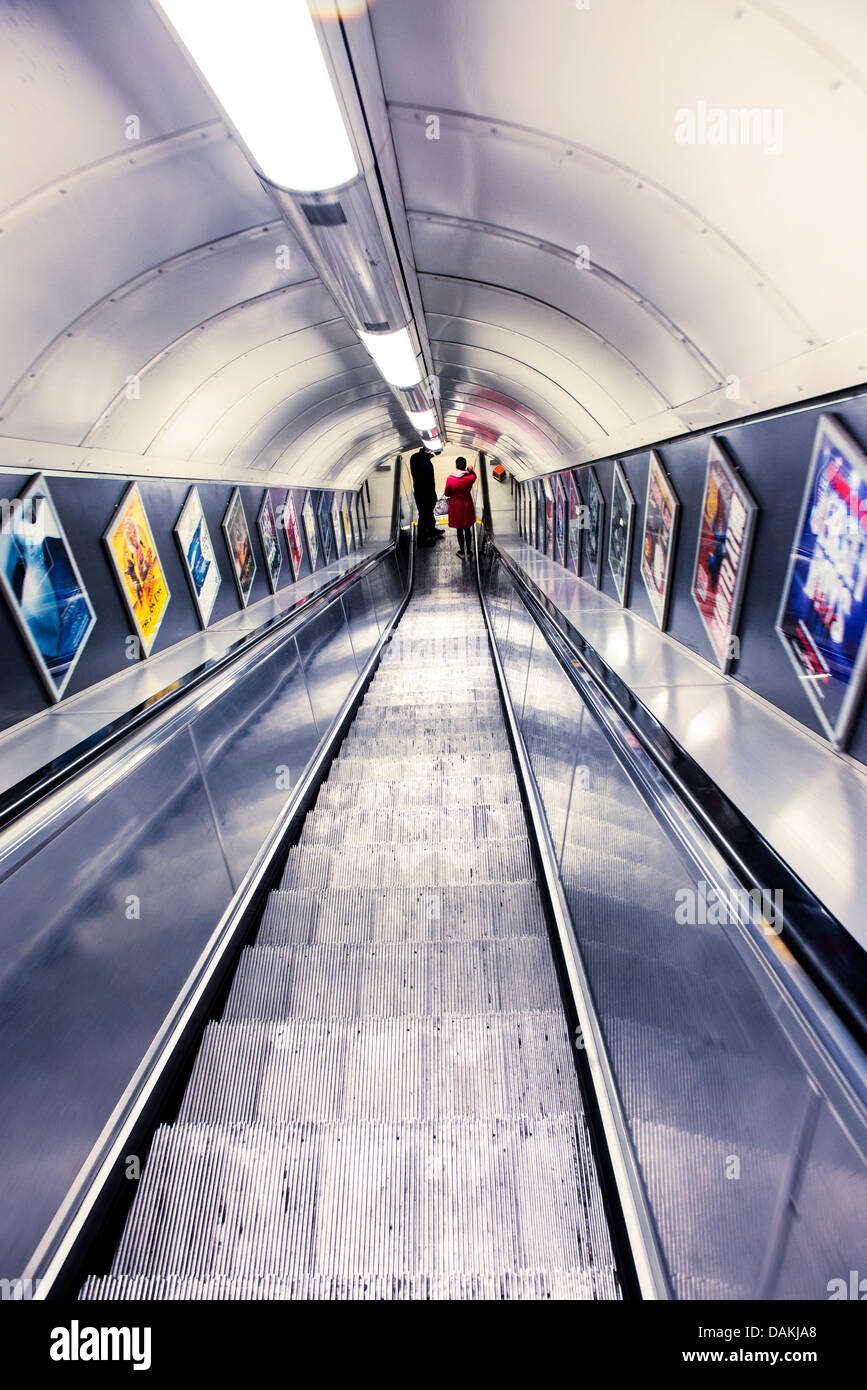 A man and a woman at the bottom of an escalator at a London underground station Stock Photo