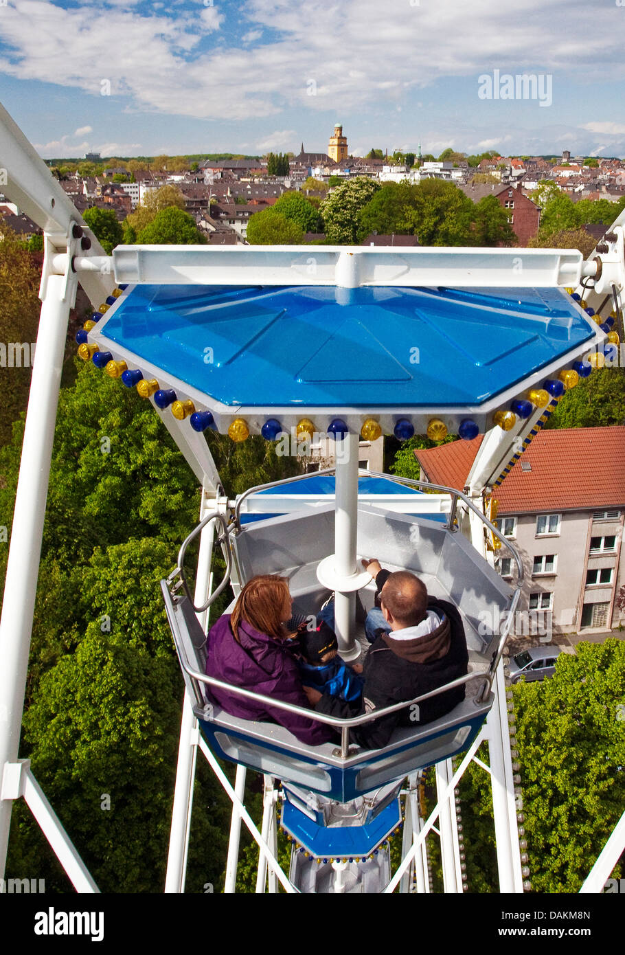 family with one child in a gondola of ferris wheel with outlook to the townhall tower, Germany, North Rhine-Westphalia, Ruhr Area, Witten Stock Photo