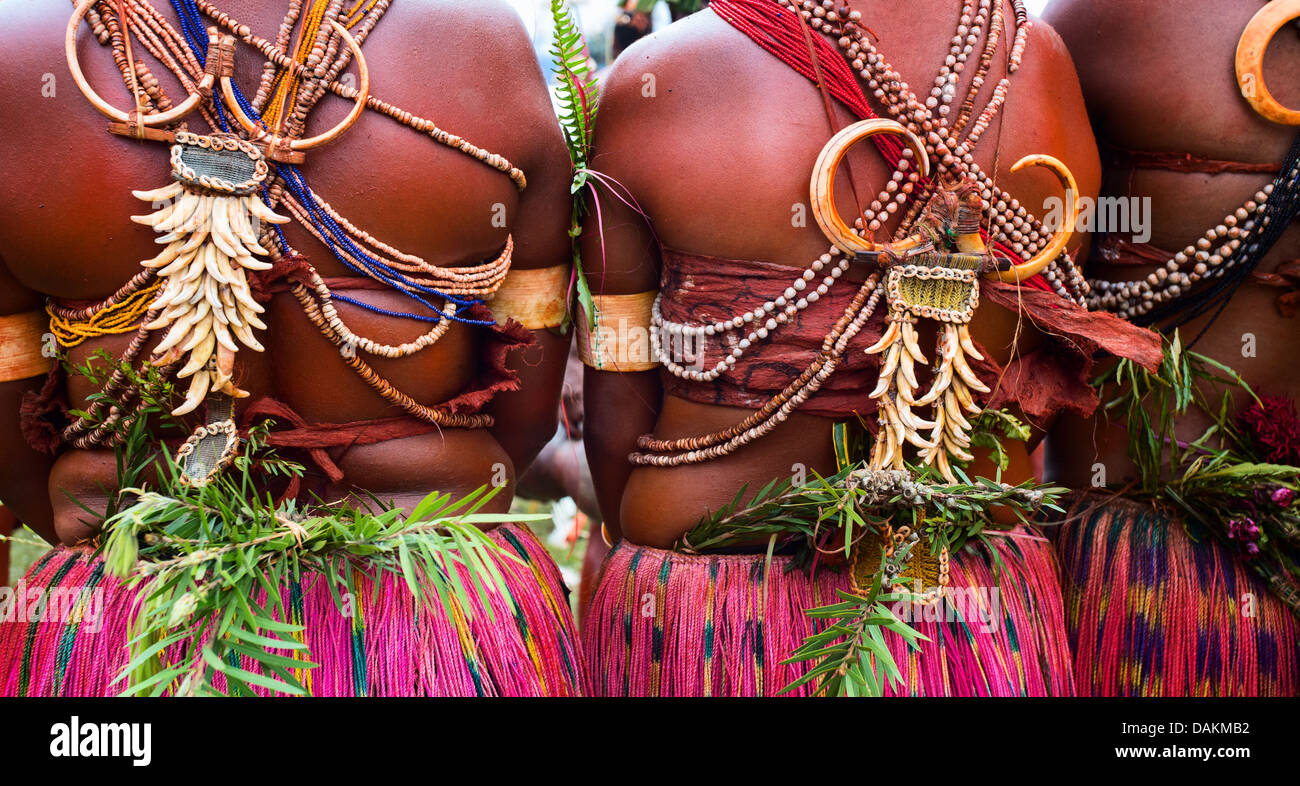 The backs of women dressed in grass skirts and wearing the teeth and tusks of animals, Goroka Show, Papua New Guinea Stock Photo