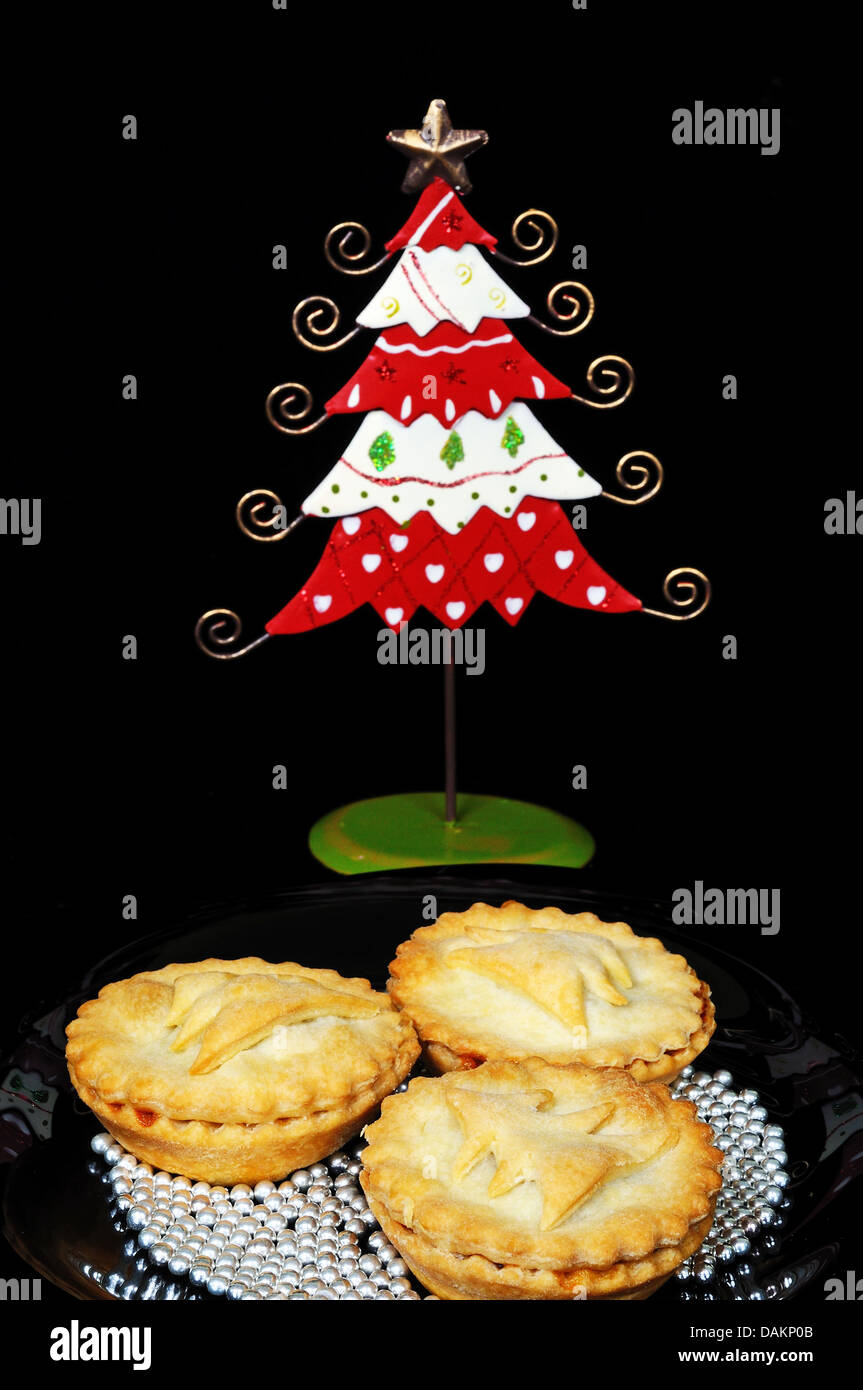Three homemade mince pies surrounded by edible silver balls with a