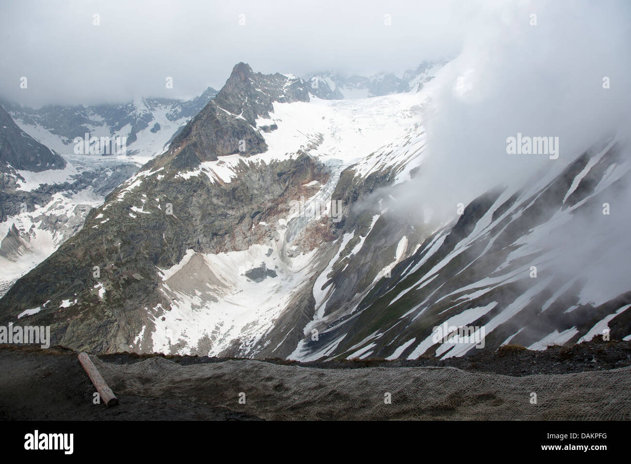 Descent of the Grandes Col Ferret with partial views of  Les Grandes Jorasses in the mist Stock Photo
