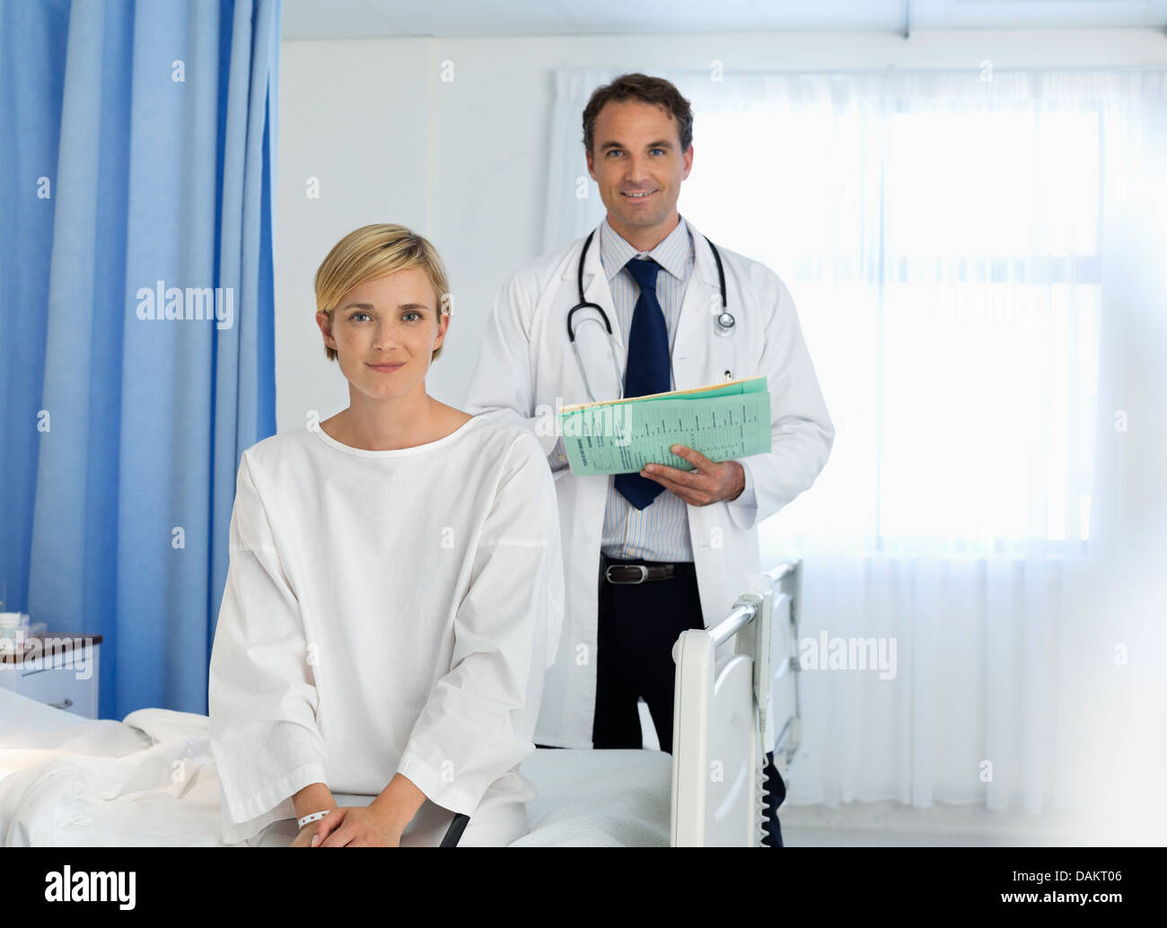 Doctor and patient smiling in hospital room Stock Photo