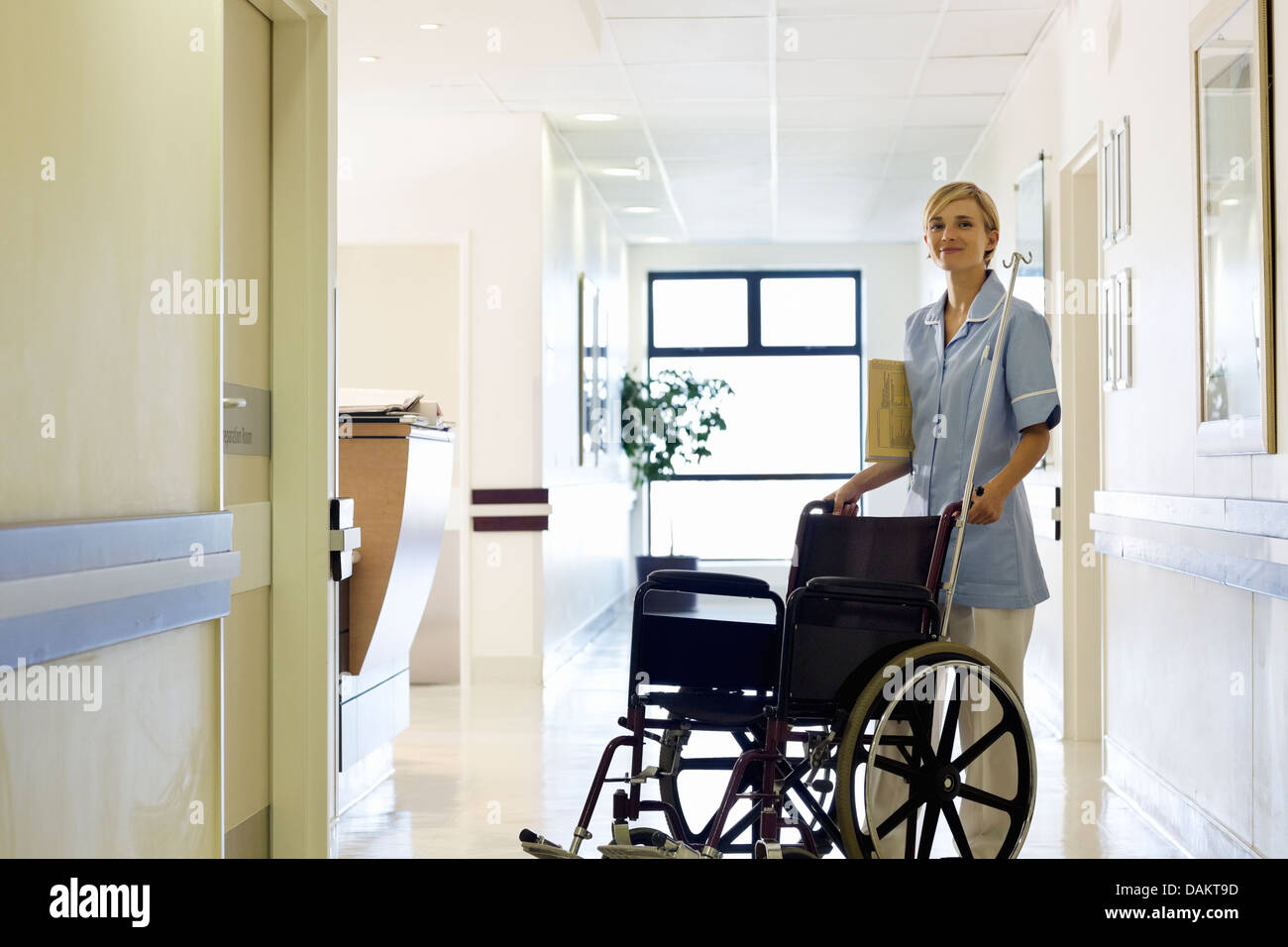 Nurse pushing wheelchair in hospital hallway Stock Photo