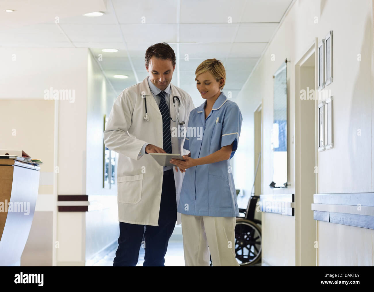 Doctor and nurse using tablet computer in hospital hallway Stock Photo