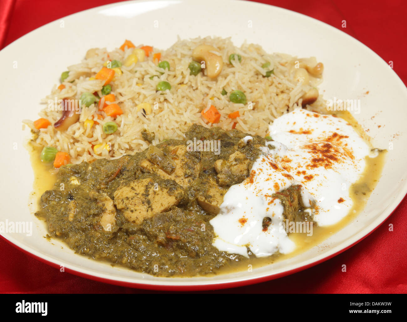 A meal of chicken saag (spinach) curry served with yoghurt and chilli