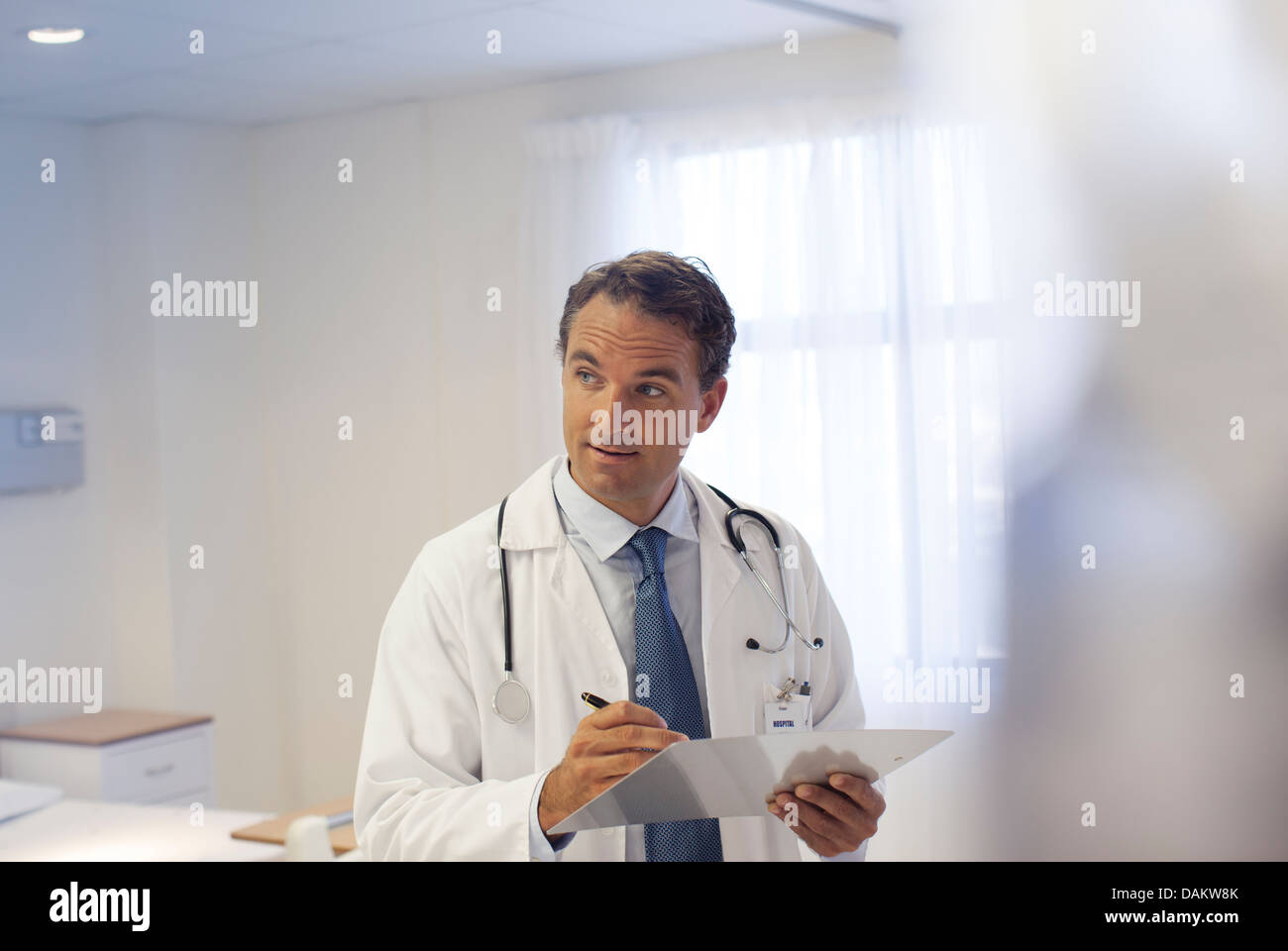 Doctor writing on clipboard in hospital Stock Photo