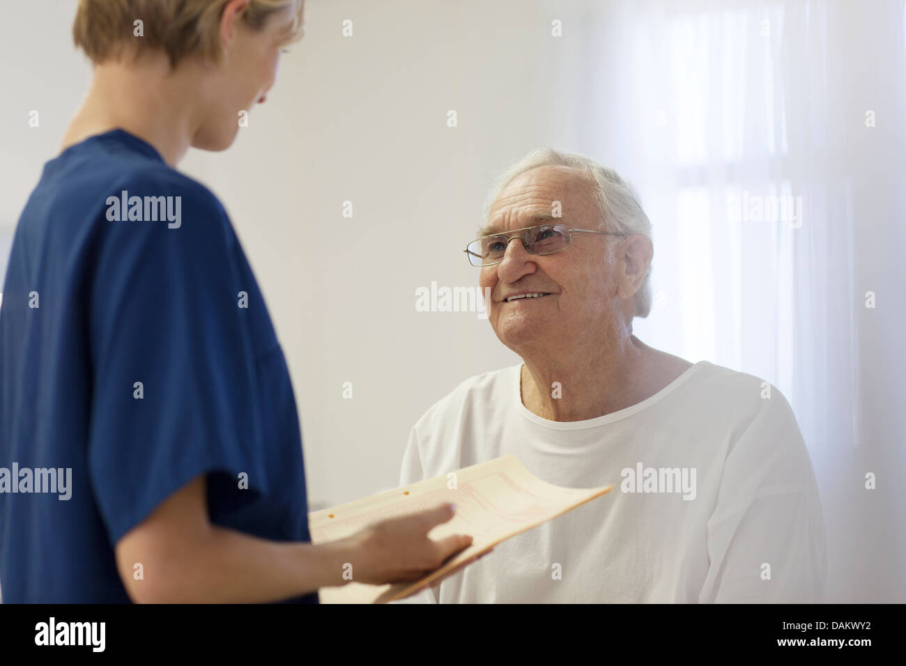 Nurse talking to older patient in hospital room Stock Photo