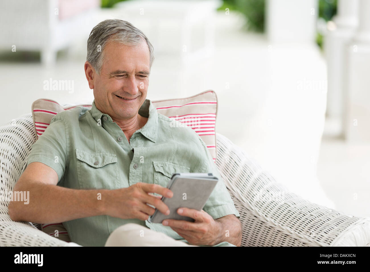 Older man using tablet computer on porch Stock Photo