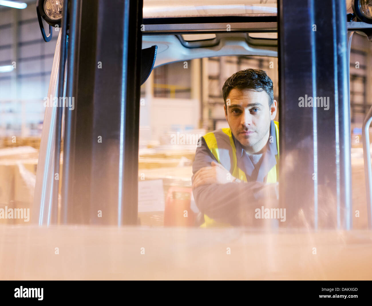 Worker operating forklift in warehouse Stock Photo