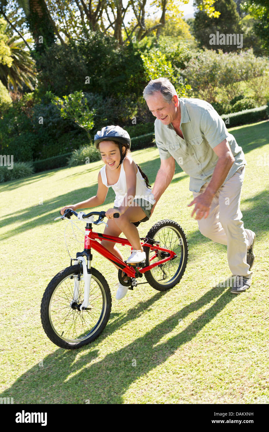 Older man teaching granddaughter to ride bicycle Stock Photo