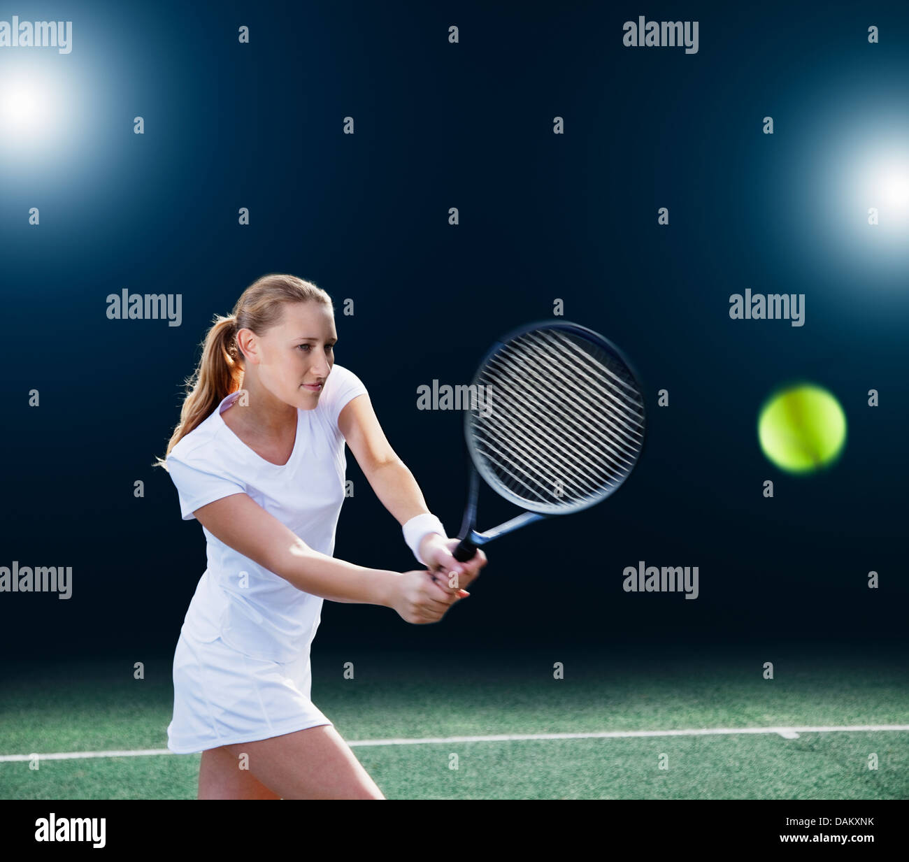 Tennis player hitting ball on court Stock Photo