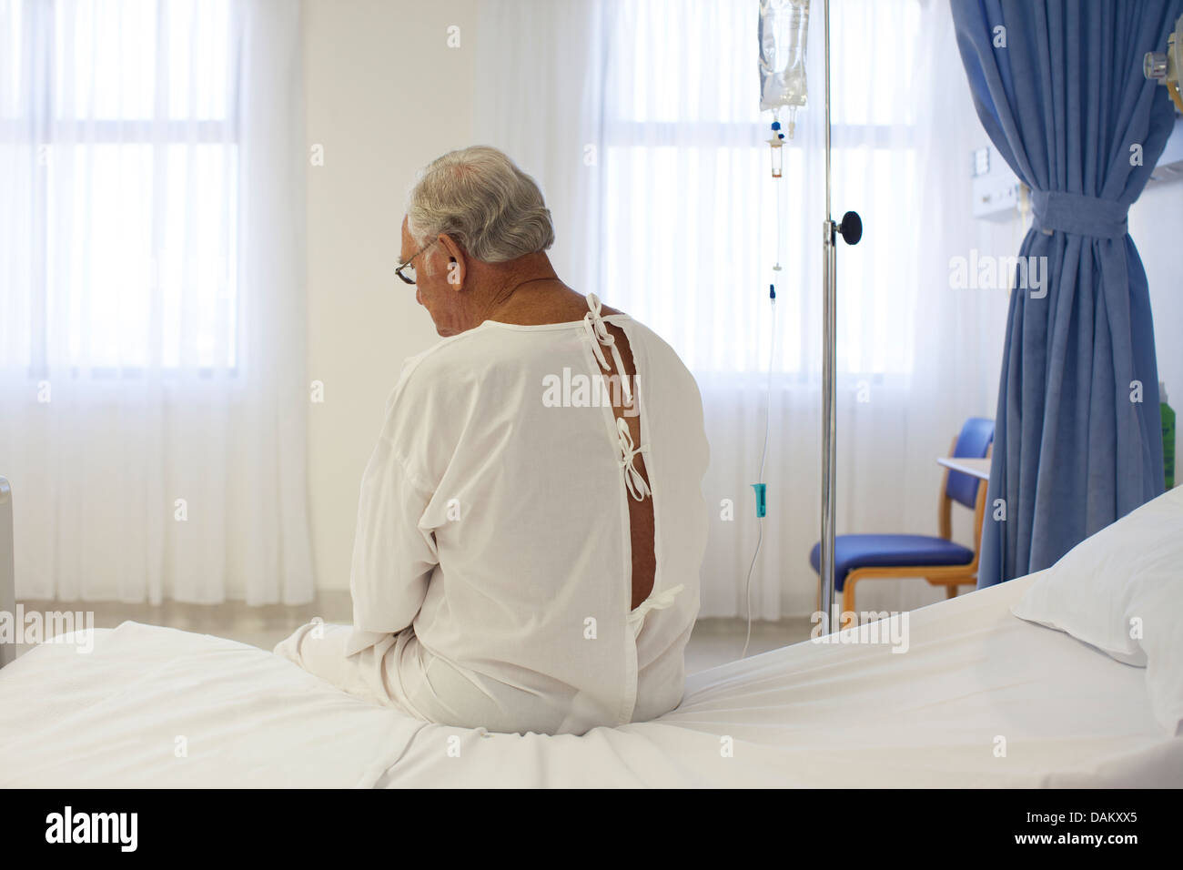 Older patient wearing gown in hospital room Stock Photo Alamy