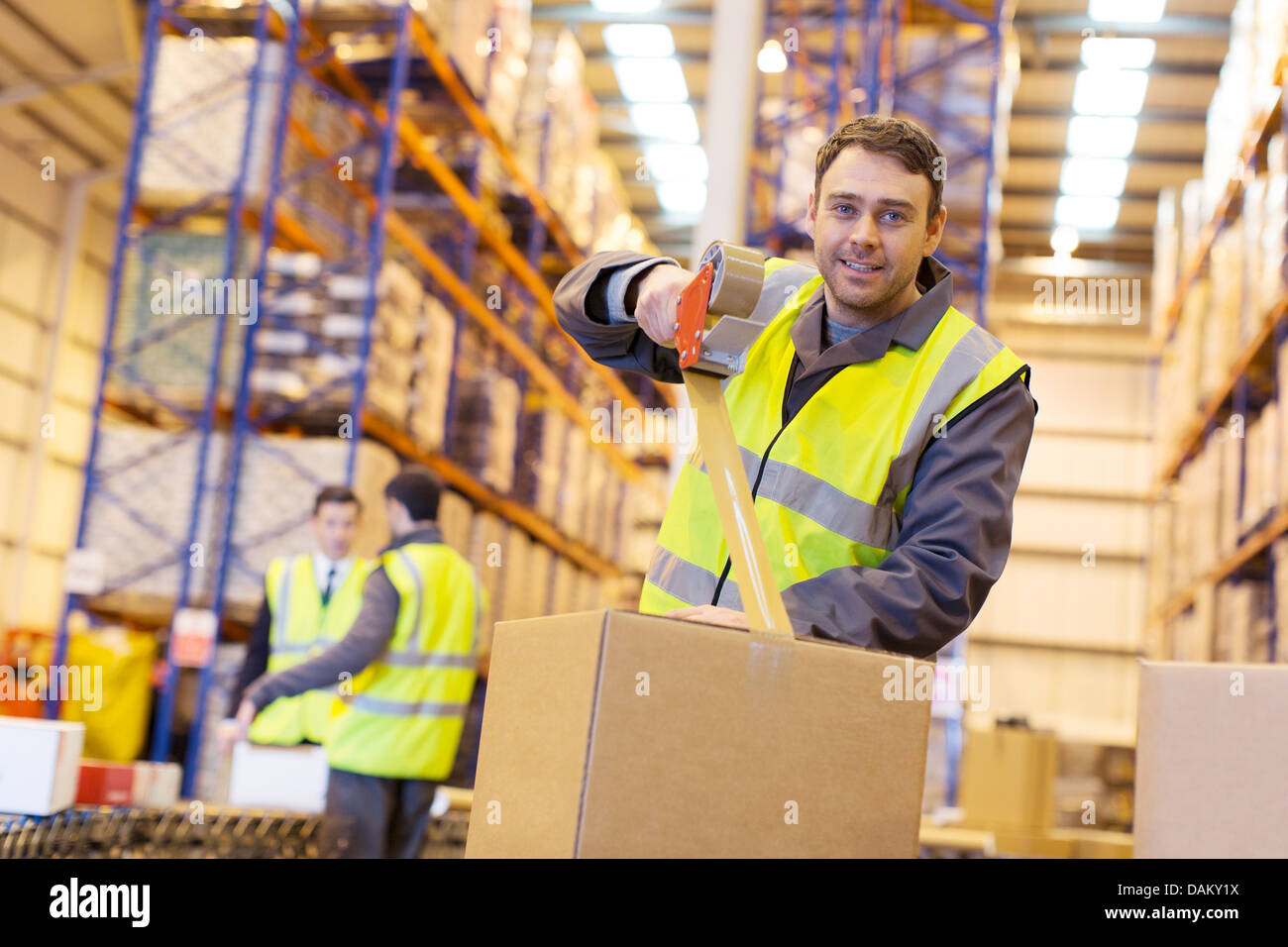 Worker taping cardboard box in warehouse Stock Photo Alamy