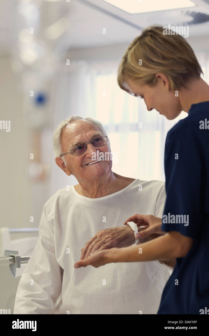 Nurse reading older patient's medical bracelet in hospital Stock Photo