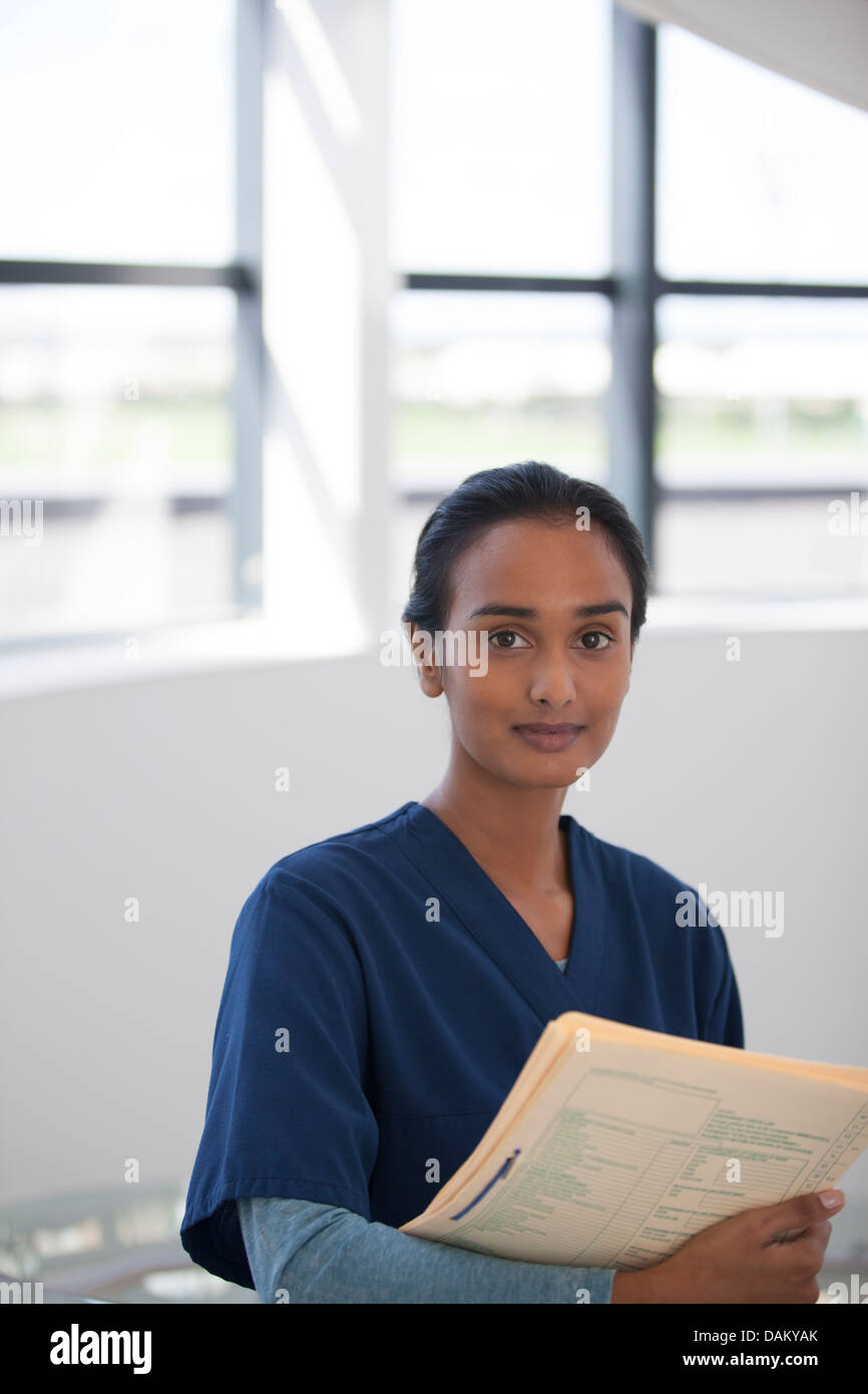 Nurse carrying folder in hospital hallway Stock Photo