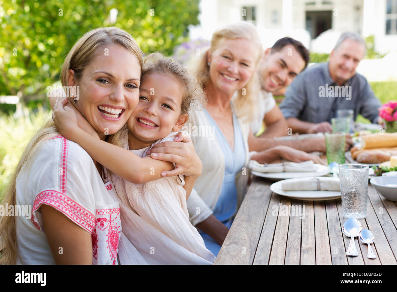 Mother and daughter hugging at table outdoors Stock Photo