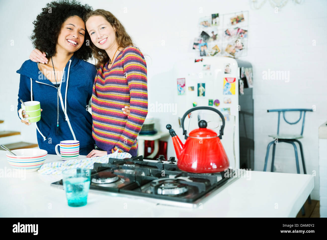 Women hugging in kitchen Stock Photo