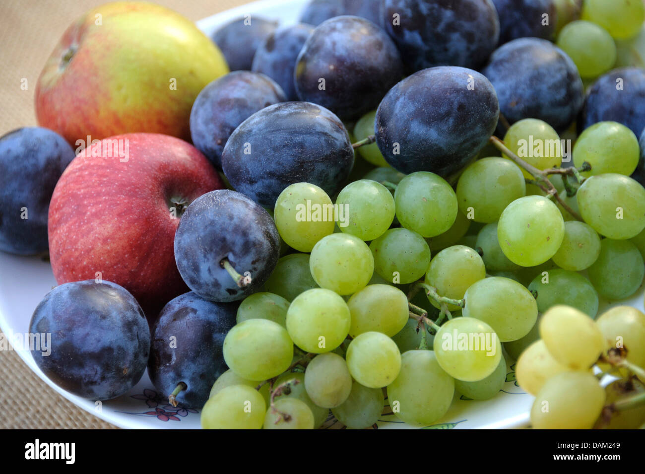 plums, apples and grapes on a plate Stock Photo