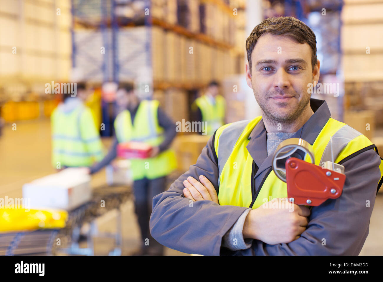 Worker holding tape dispenser in warehouse Stock Photo