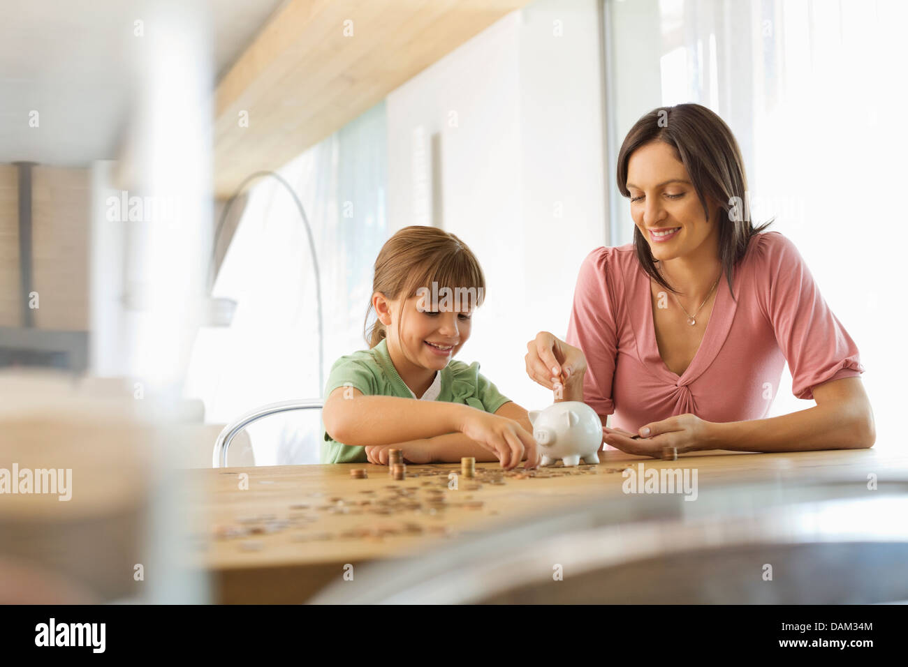Mother and daughter filling piggy bank Stock Photo - Alamy