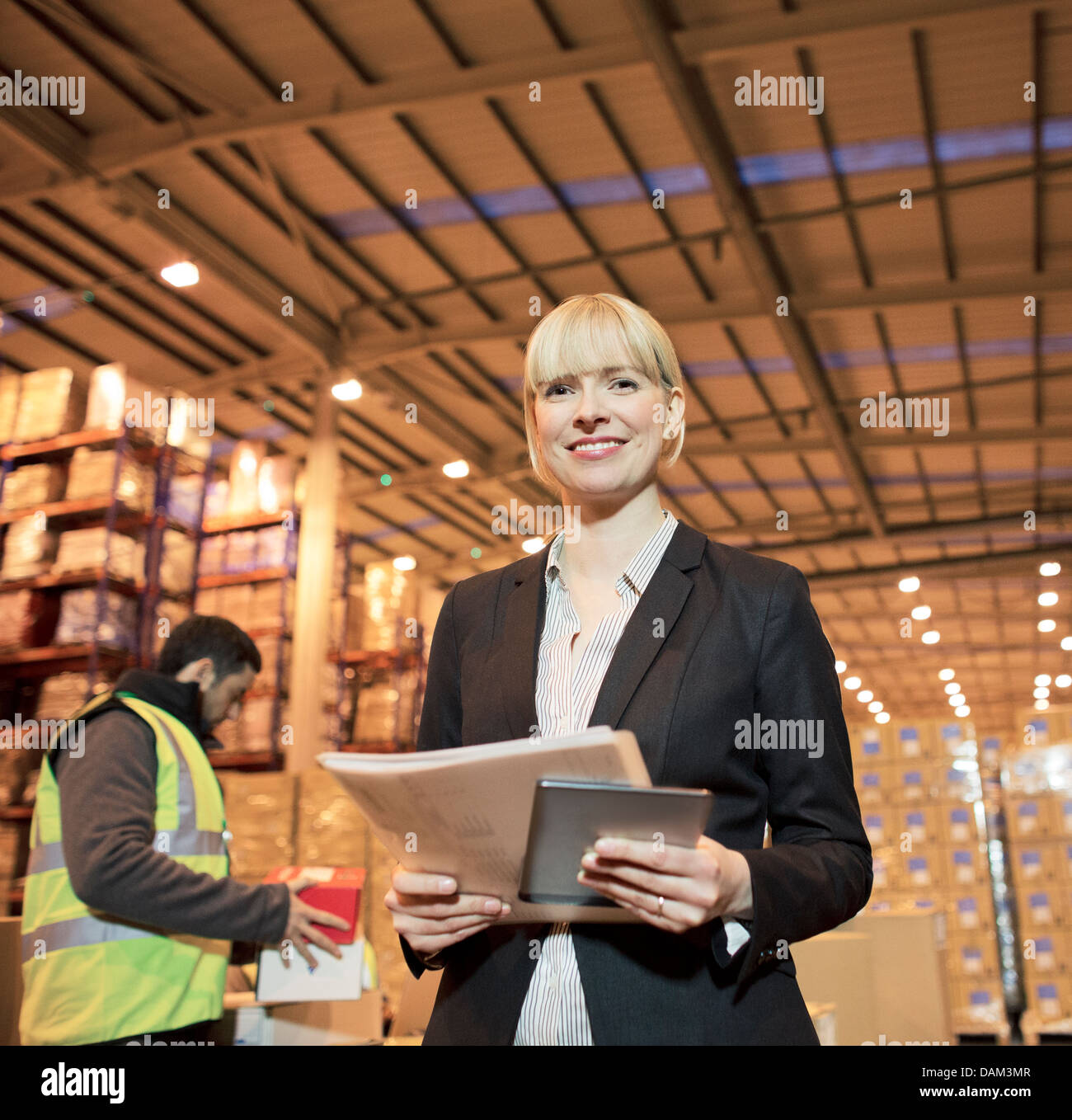 Businesswoman with folder and tablet computer in warehouse Stock Photo