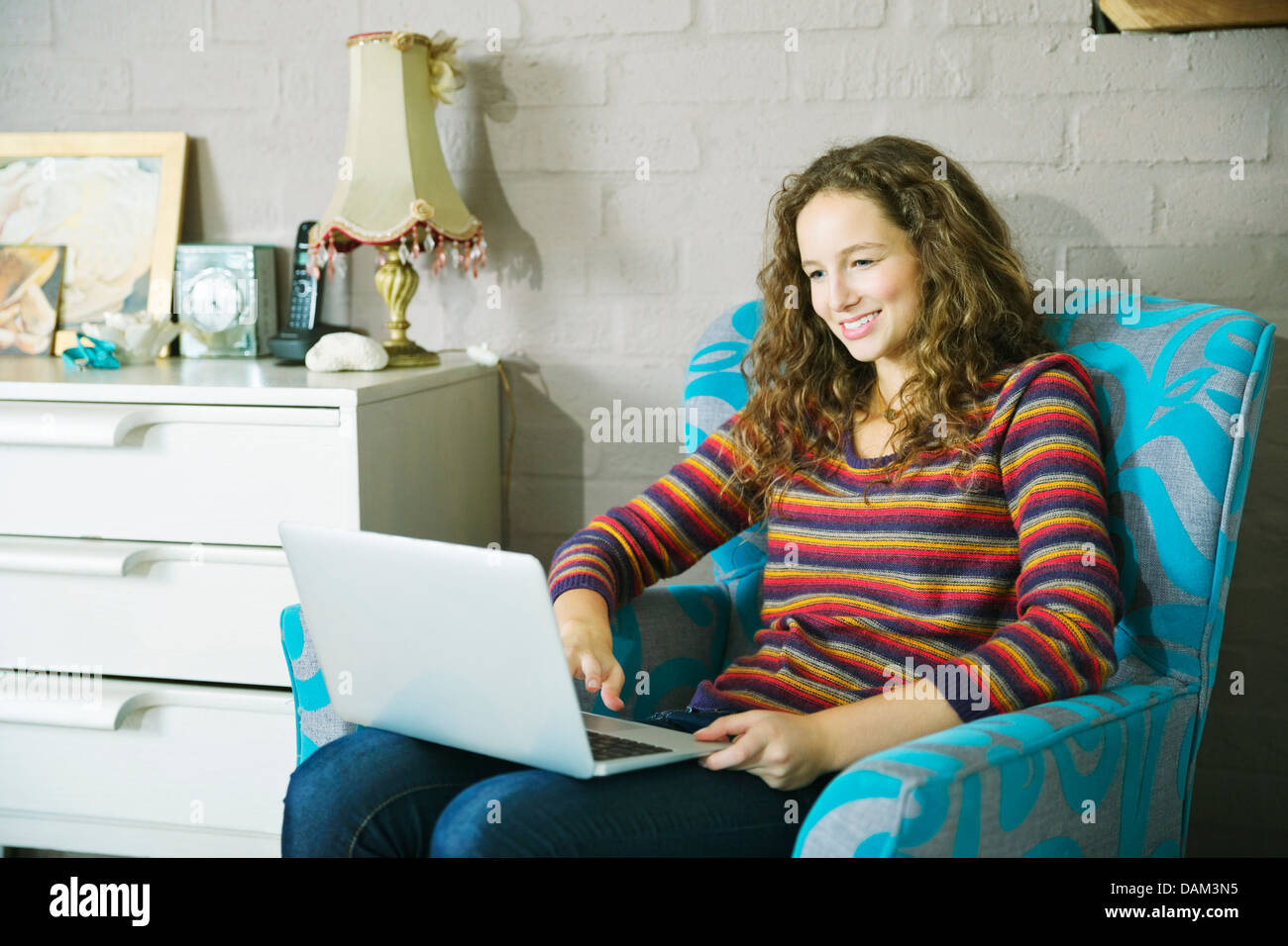 Woman using laptop in armchair Stock Photo