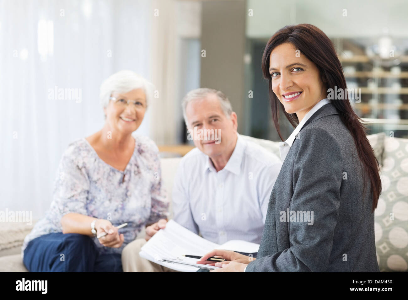 Financial advisor talking to couple on sofa Stock Photo