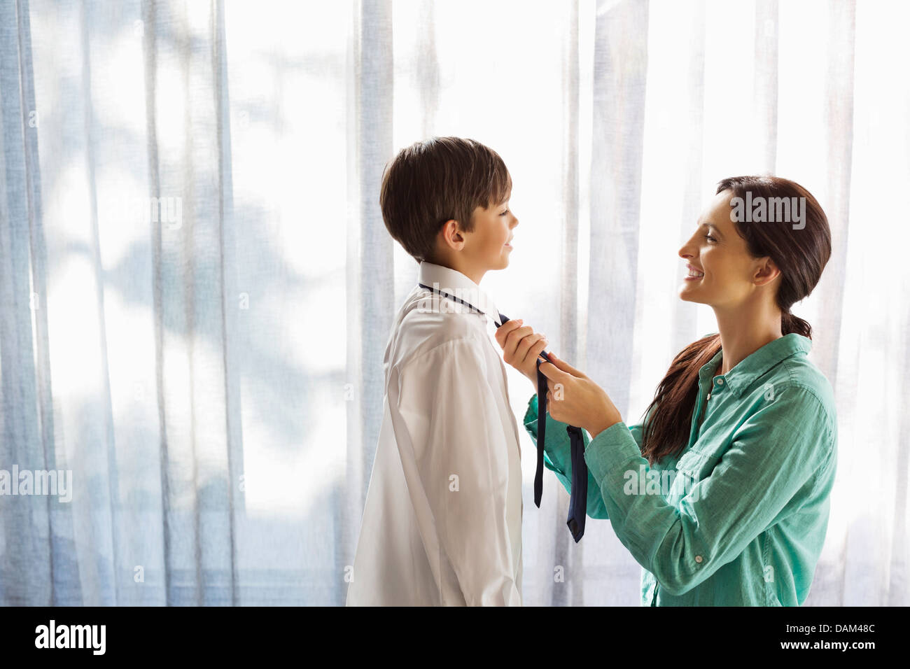 Mother tying son's tie at window Stock Photo