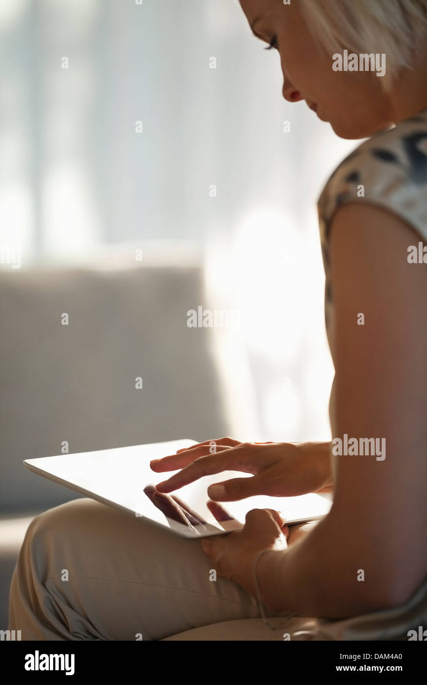 Woman using tablet computer on sofa Stock Photo