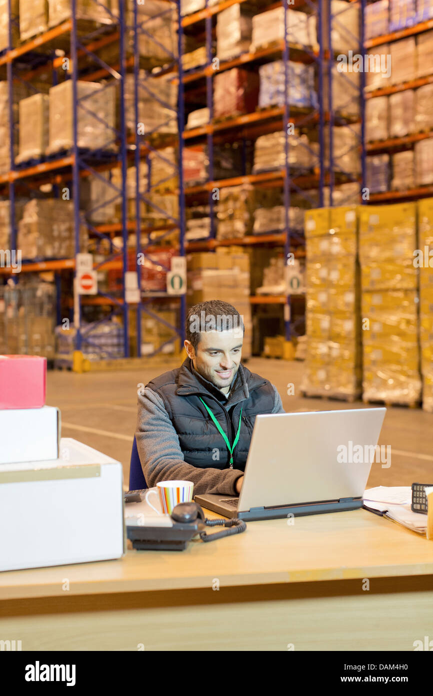 Worker using laptop in warehouse Stock Photo