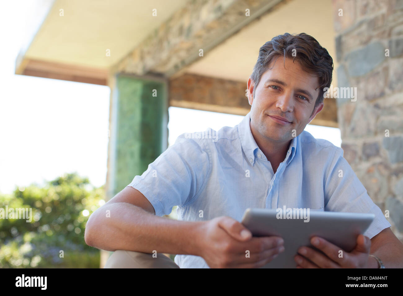 Man using tablet computer on porch Stock Photo