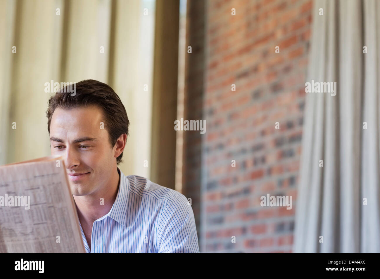 Businessman reading newspaper indoors Stock Photo