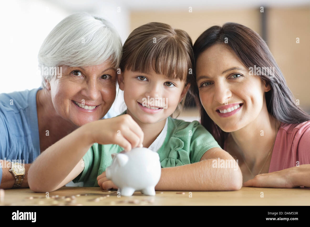 Three generations of women filling piggy bank Stock Photo