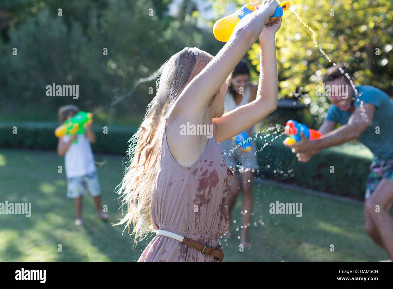 Family playing with water guns in backyard Stock Photo