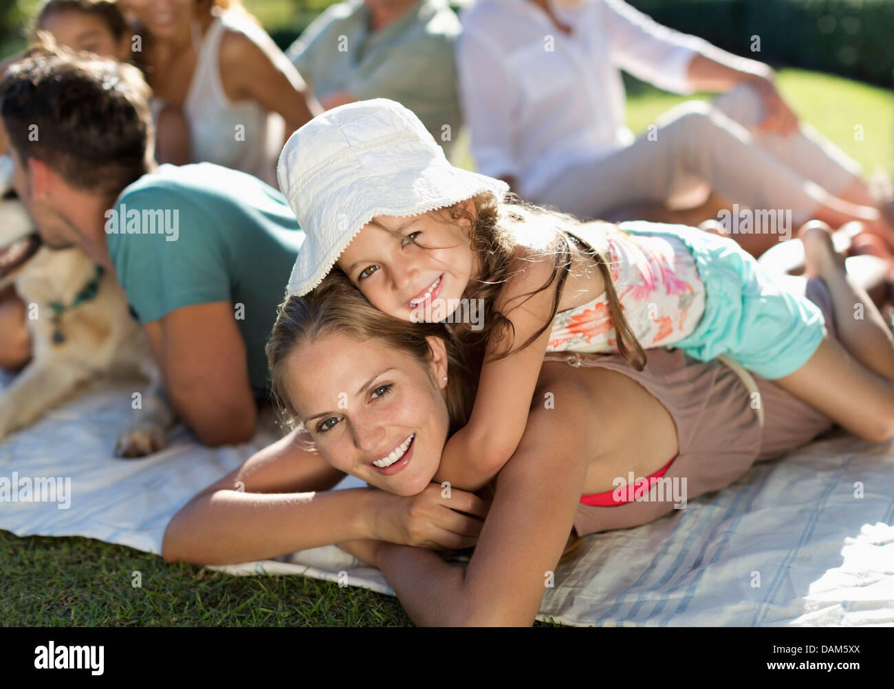 Mother and daughter relaxing in grass with family Stock Photo