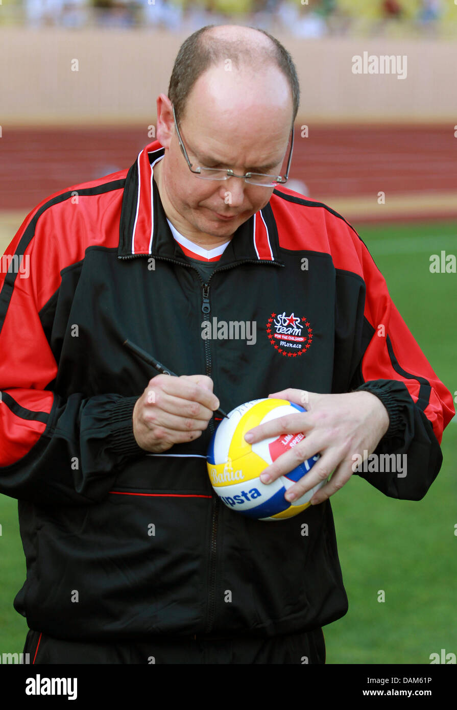 Prince Albert II of Monaco signs his autograph onto a soccer ball during a charity football match between racing drivers and celebrities prior to the Formula One Grand Prix of Monaco in Monte Carlo, Monaco, 24 May 2011. The Grand Prix will take place on 29 May. Photo: Jens Buettner dpa Stock Photo